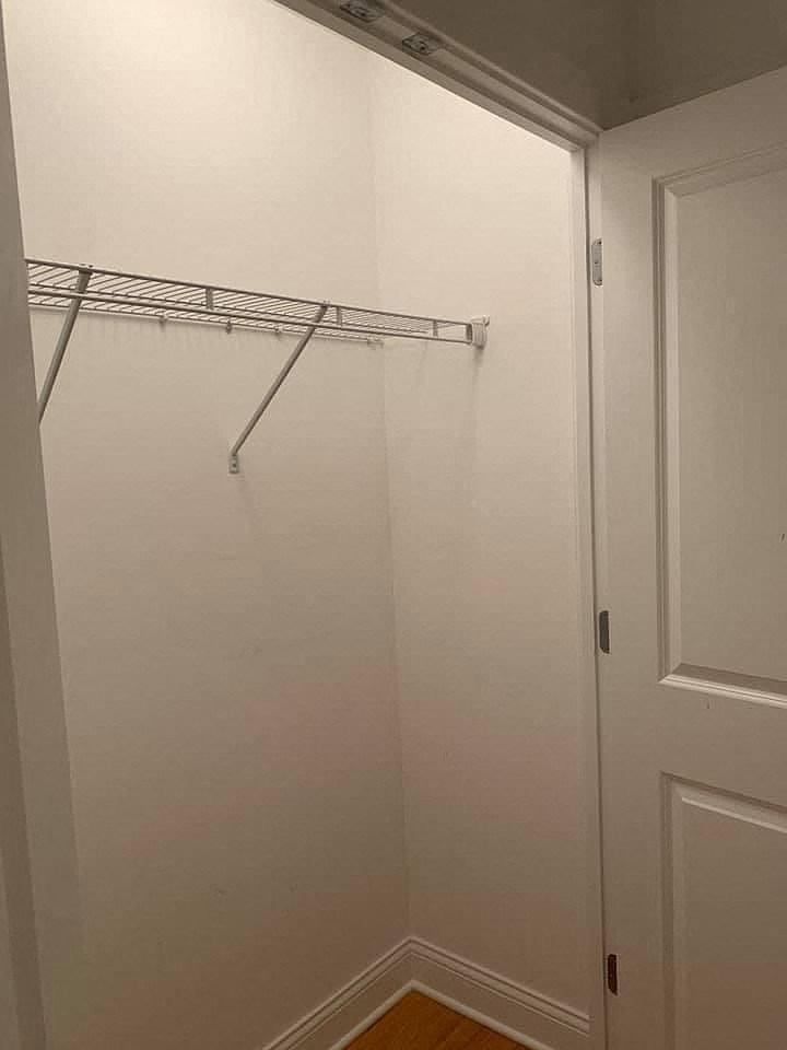 a white closet with a white door and a hanging rack
