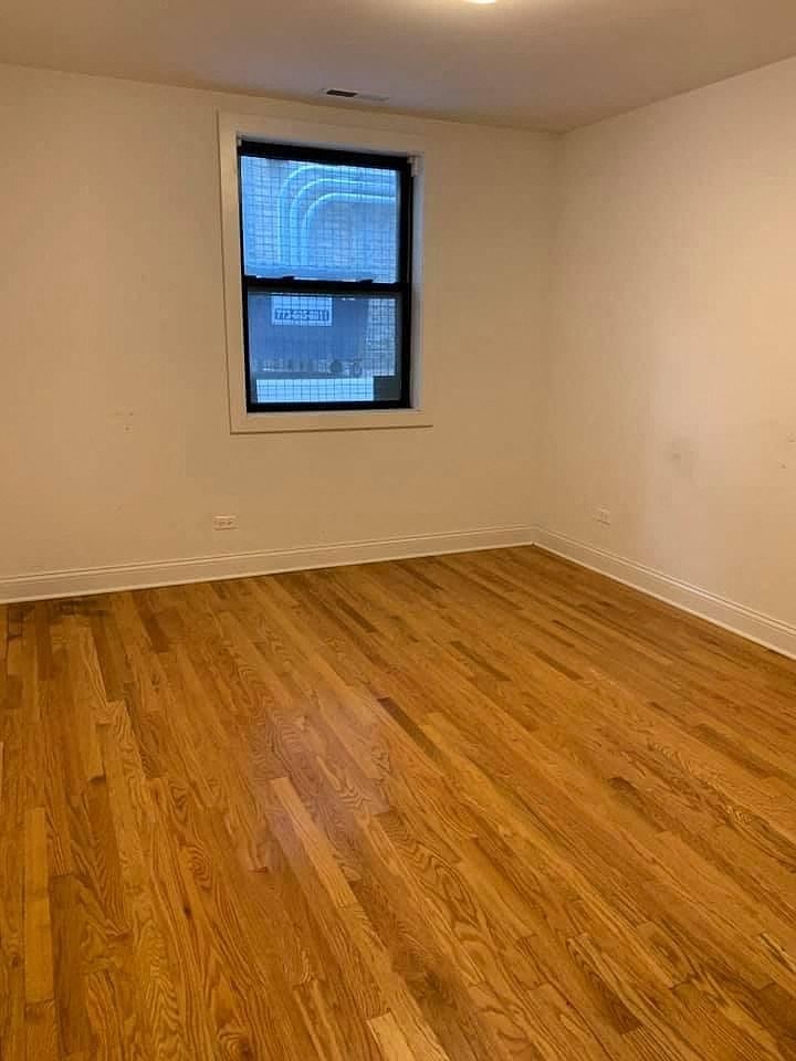 an empty room with a window and wooden floors