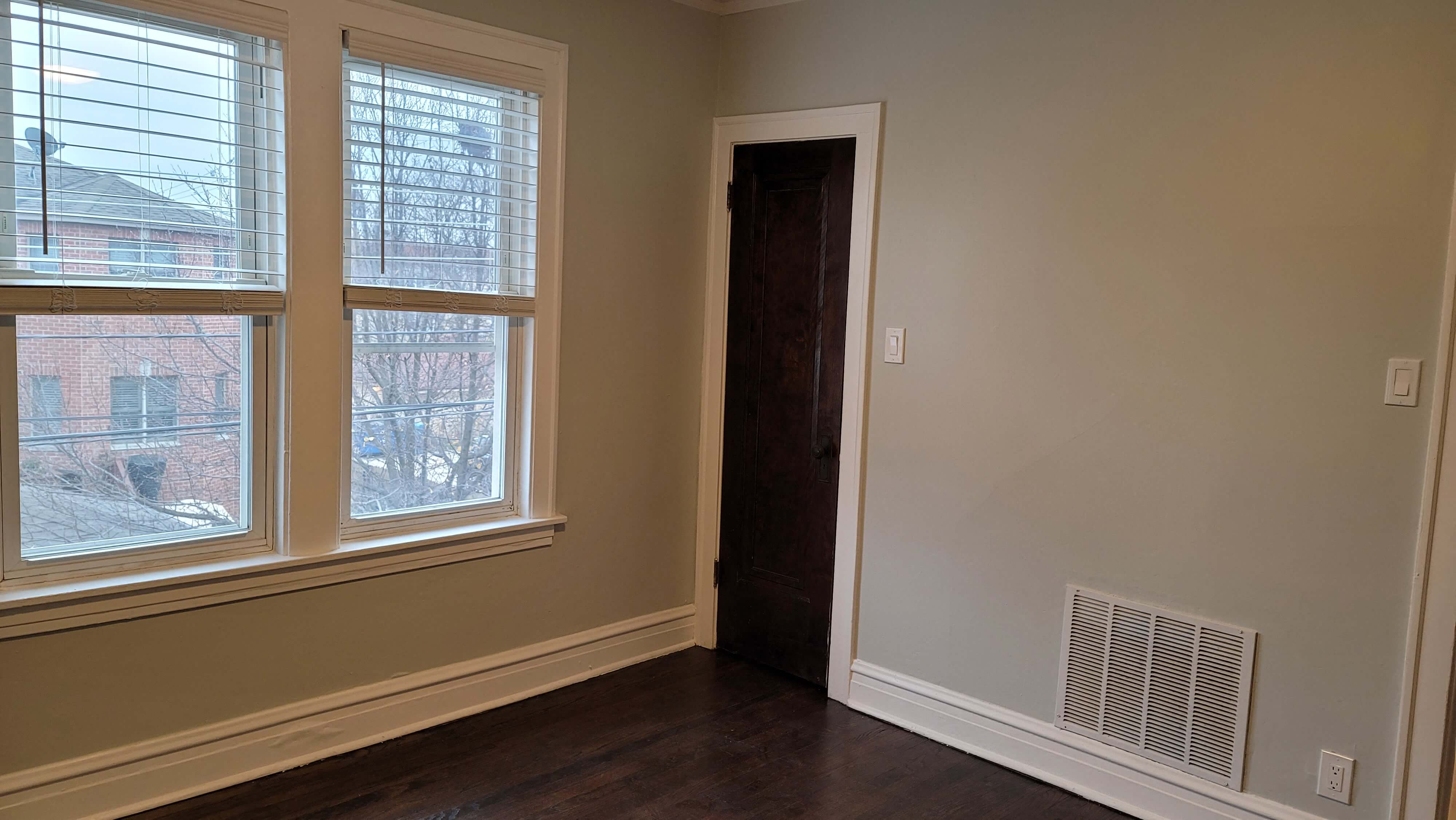 A room with a brown door and a window with blinds.
