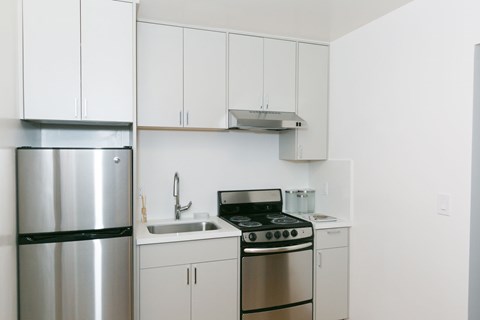 A kitchen with white cabinets and a stainless steel refrigerator.