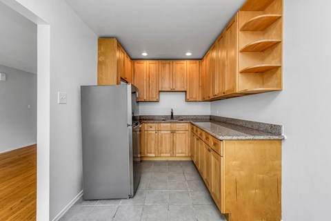 A kitchen with wooden cabinets and a grey refrigerator.