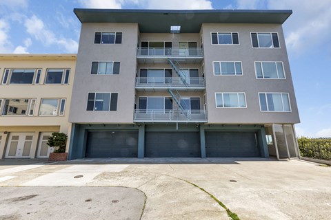 A multi-story apartment building with a parking lot in front.