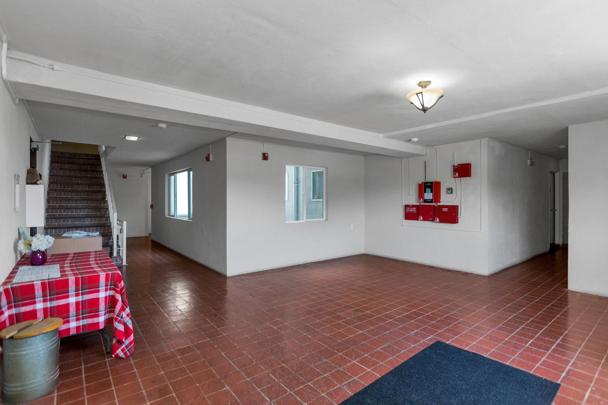 A room with red tiled floors and a table with a red and white checkered tablecloth.