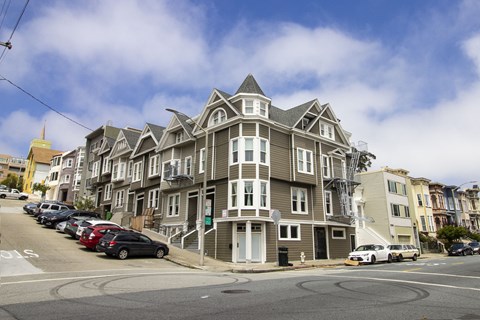 A large, multi-story building with a grey and white exterior sits on a street corner.