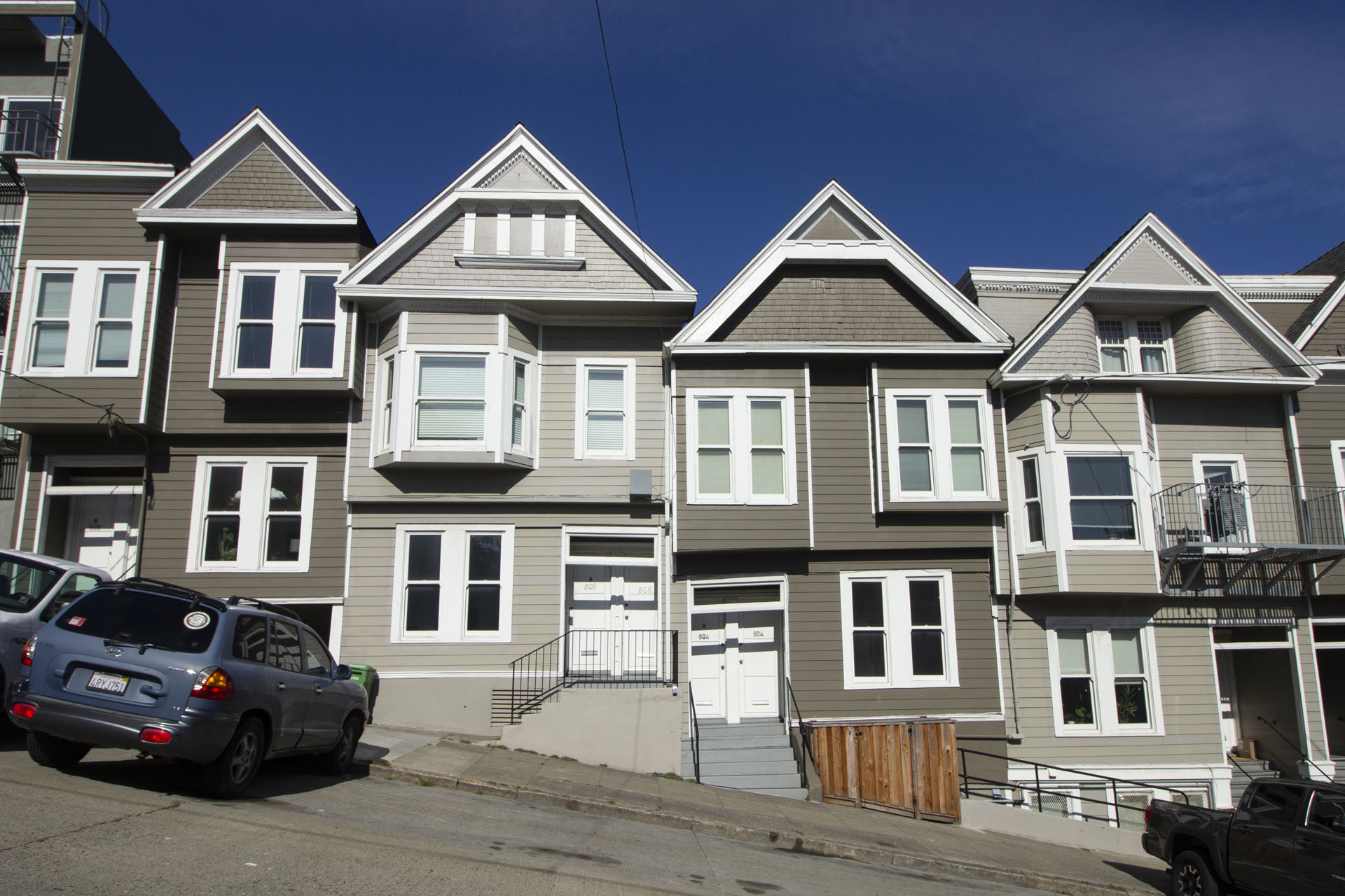 A row of townhouses with cars parked in front.