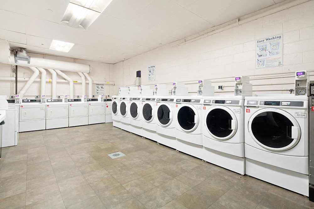 a row of washers and dryers in a laundry room with many washing machines
