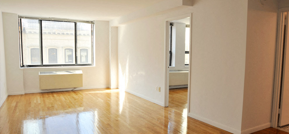 an empty living room with a window and wood floors