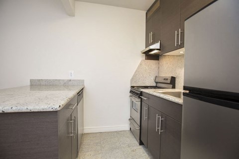 an empty kitchen with stainless steel appliances and marble counter tops