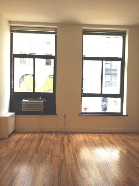 an empty living room with two windows and a air conditioner
