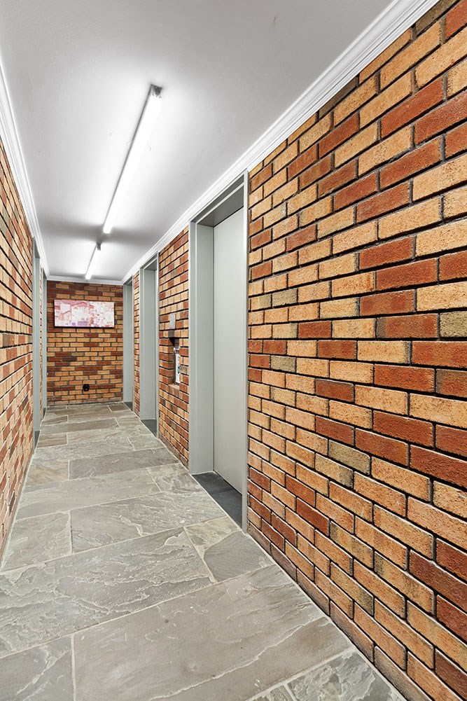 a long hallway with brick walls and a concrete floor