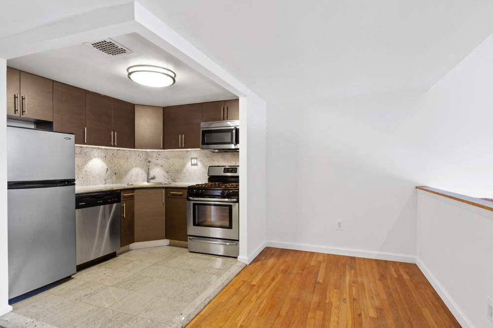 a kitchen with stainless steel appliances and wooden floors