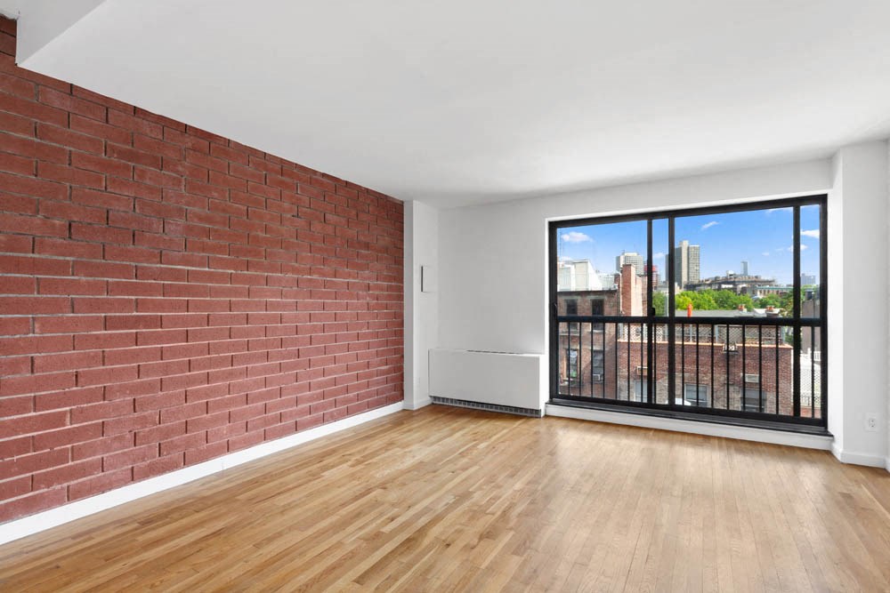 an empty living room with a brick wall and a balcony
