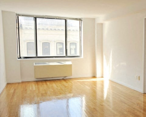 an empty living room with a wood floor and a window
