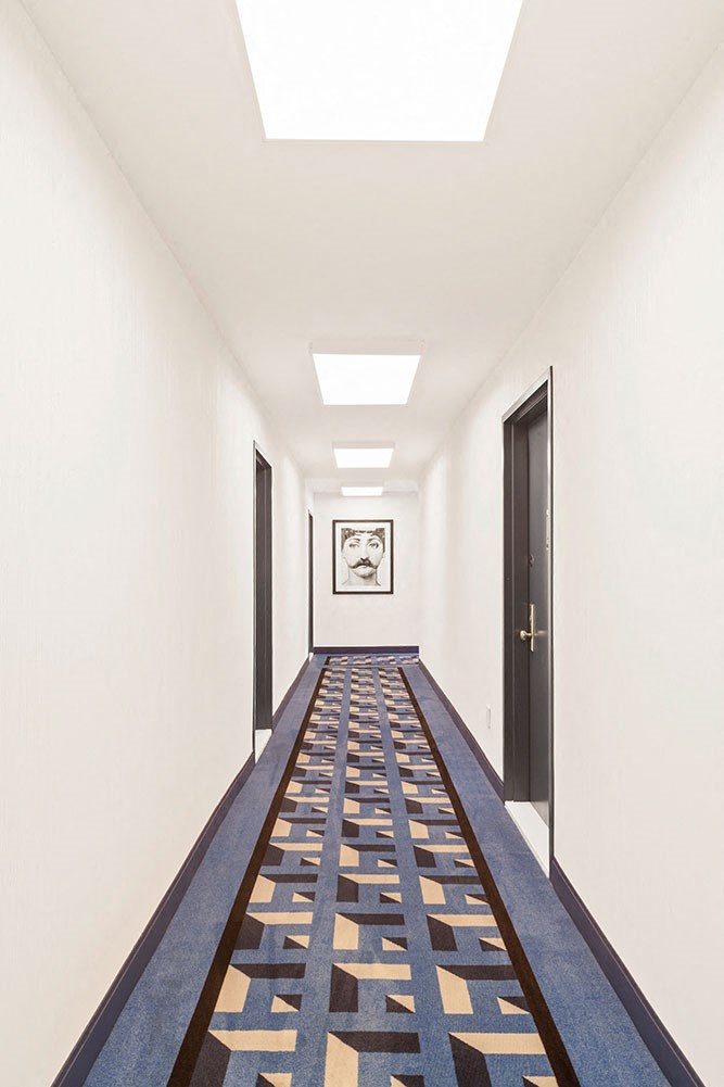 a long corridor with a blue and yellow carpet and doors