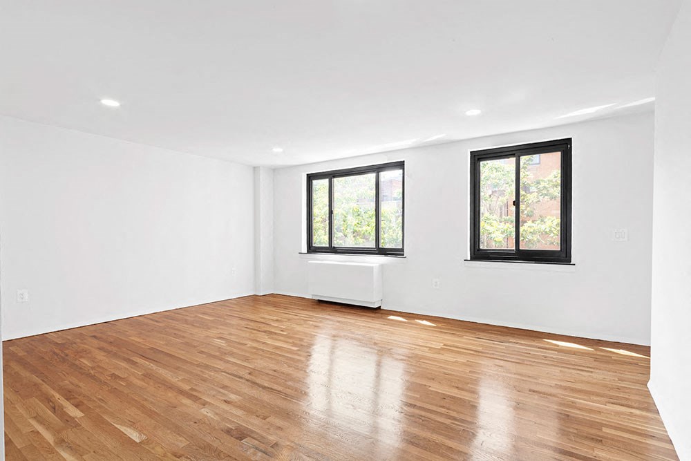 an empty living room with wood floors and a window
