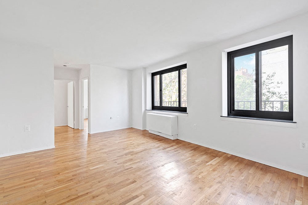 an empty living room with wood floors and a window