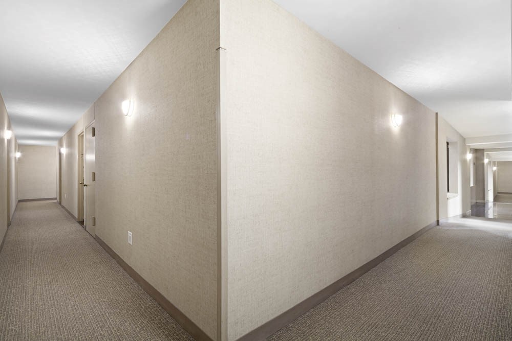 the hallway of a hotel room with white walls and a carpet