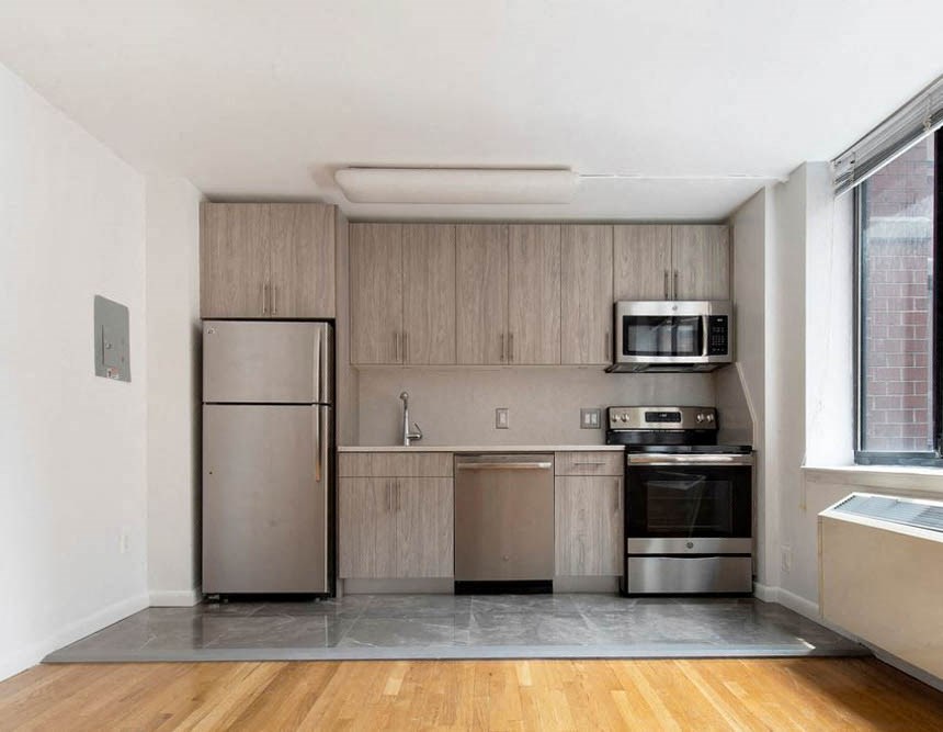 an empty kitchen with stainless steel appliances and a window