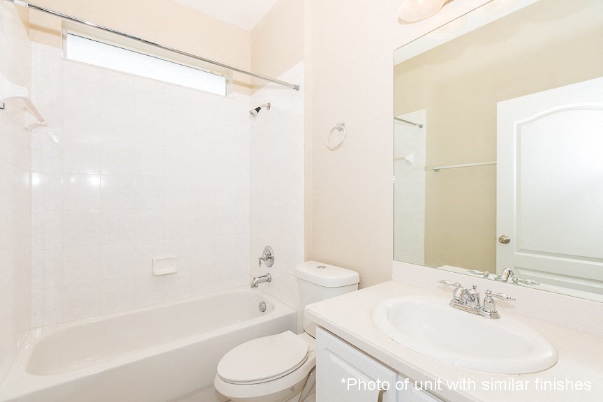 A white bathroom with a toilet, sink, and bathtub.