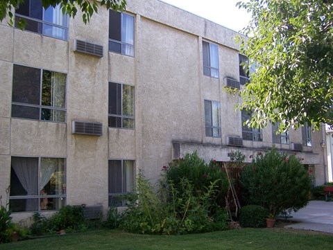 the side of an apartment building with a garden in front