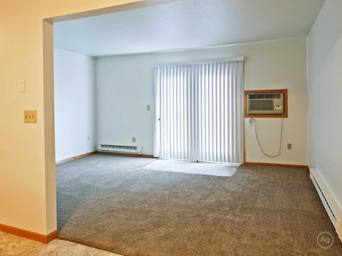 an empty living room with a window and a air conditioner