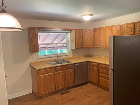 A kitchen with wooden cabinets and a black refrigerator.