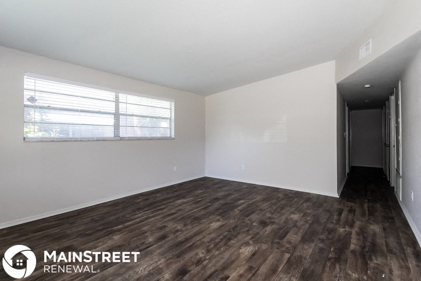 the living room of an apartment with wood flooring and a window