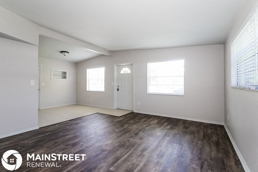 an empty living room with wood flooring and white walls