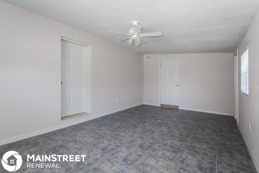 the living room of an empty house with a ceiling fan