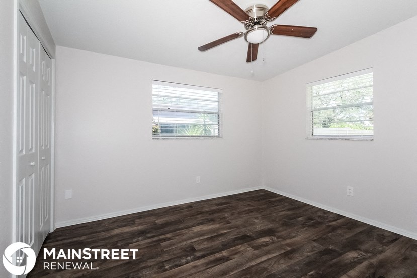 the interior of a white room with a ceiling fan and two windows