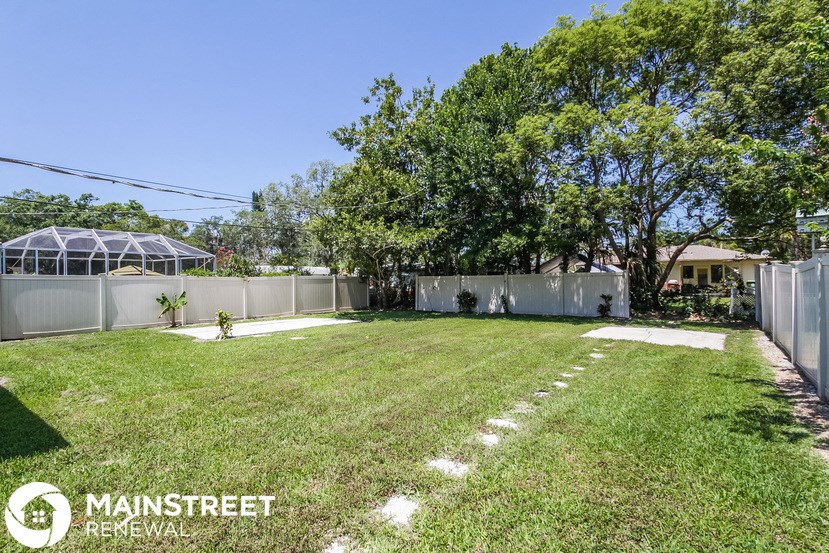 a backyard with grass and a fence and a tree