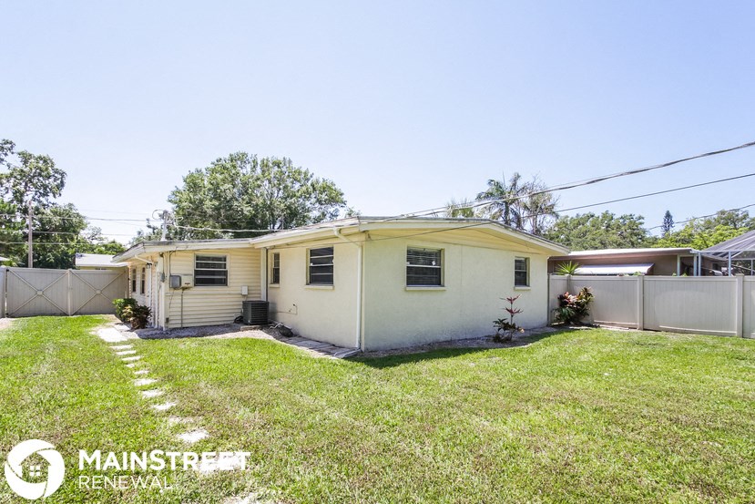 a small white house with a yard and a fence