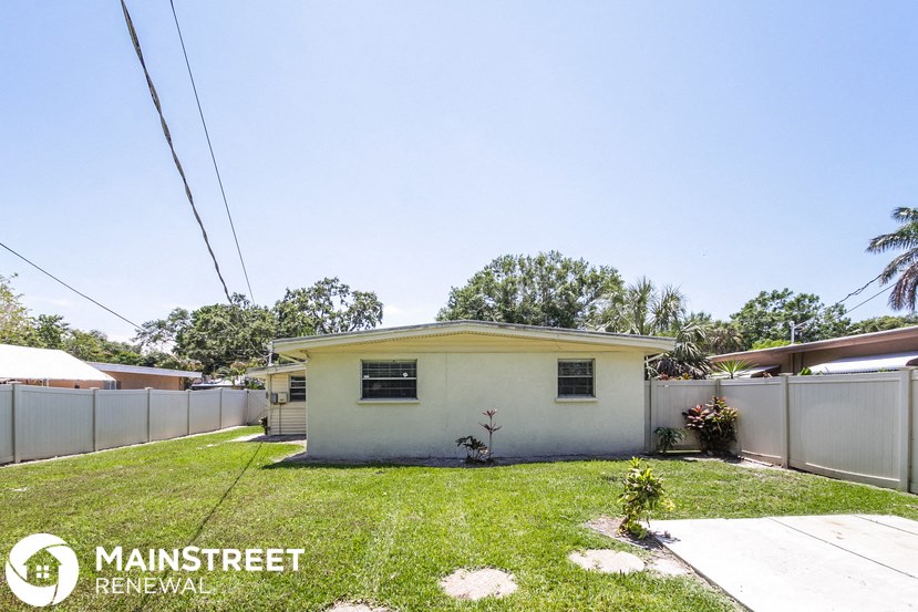 a small white house with a yard and a fence
