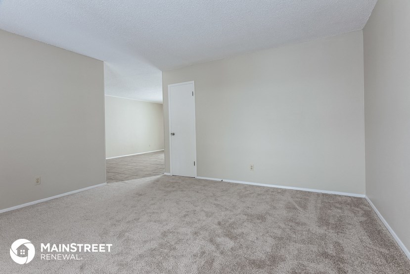 a spacious living room with carpet and white walls
