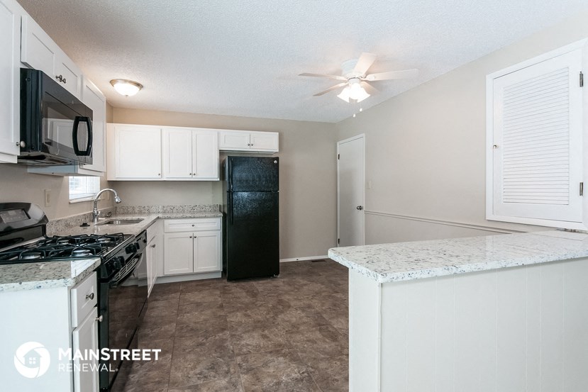 a kitchen with white cabinets and a black refrigerator