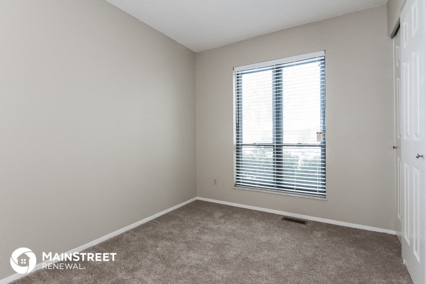 a bedroom with a large window and a carpeted floor