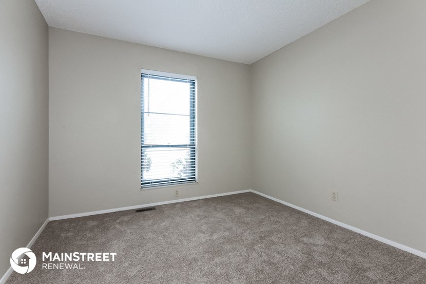 the spacious bedroom with carpeted flooring and window
