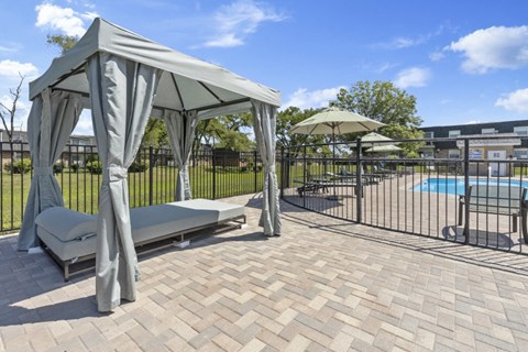 a gazebo with lounge chairs and umbrellas next to a pool