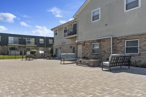 a patio with chairs and a fire pit in front of a house