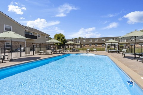 a swimming pool with umbrellas and chairs near a building