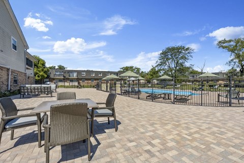 a patio with tables and chairs next to a pool