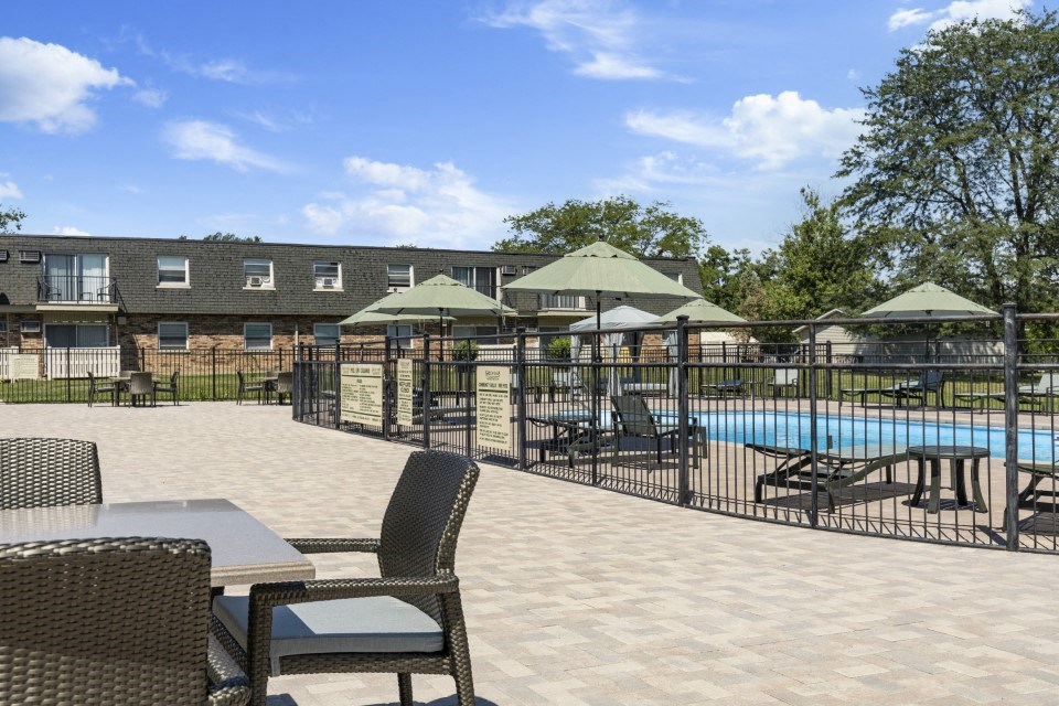 a swimming pool with patio furniture and umbrellas