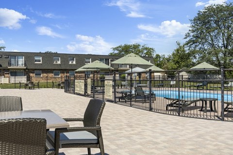 a swimming pool with patio furniture and umbrellas