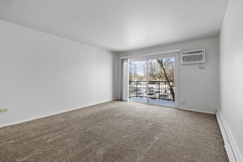 an empty living room with a sliding glass door to a balcony