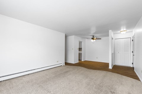 an empty living room with white walls and a ceiling fan