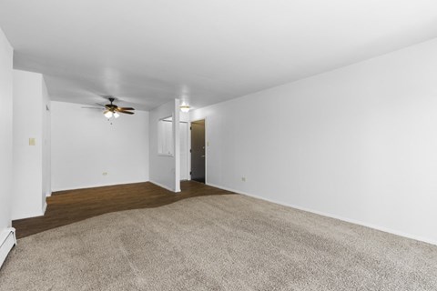 an empty living room with white walls and a ceiling fan