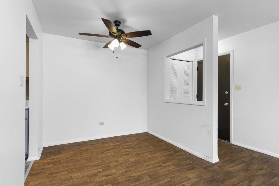 a living room with white walls and a ceiling fan
