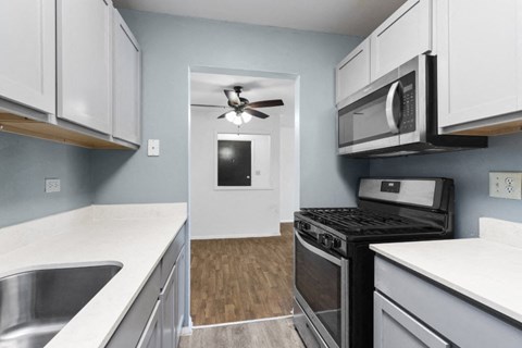 a renovated kitchen with white cabinets and stainless steel appliances and a ceiling fan