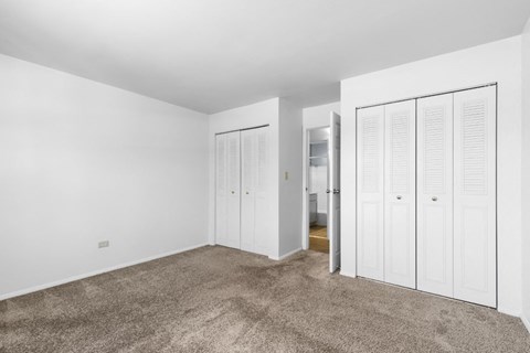 a bedroom with white closet doors and a carpeted floor