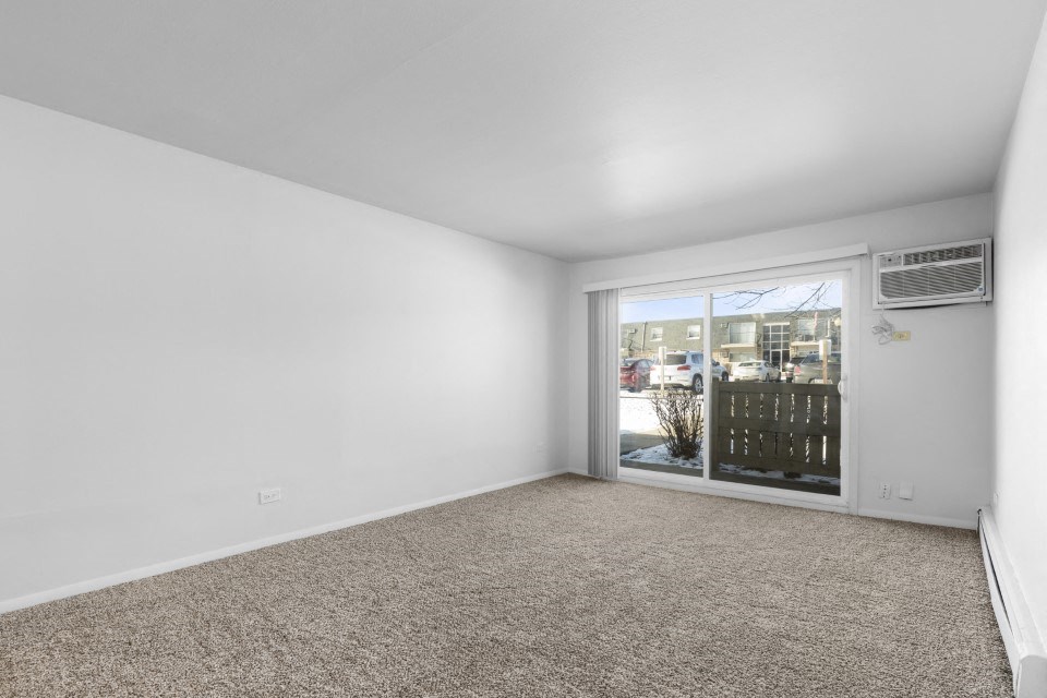 an empty living room with a large window and carpet